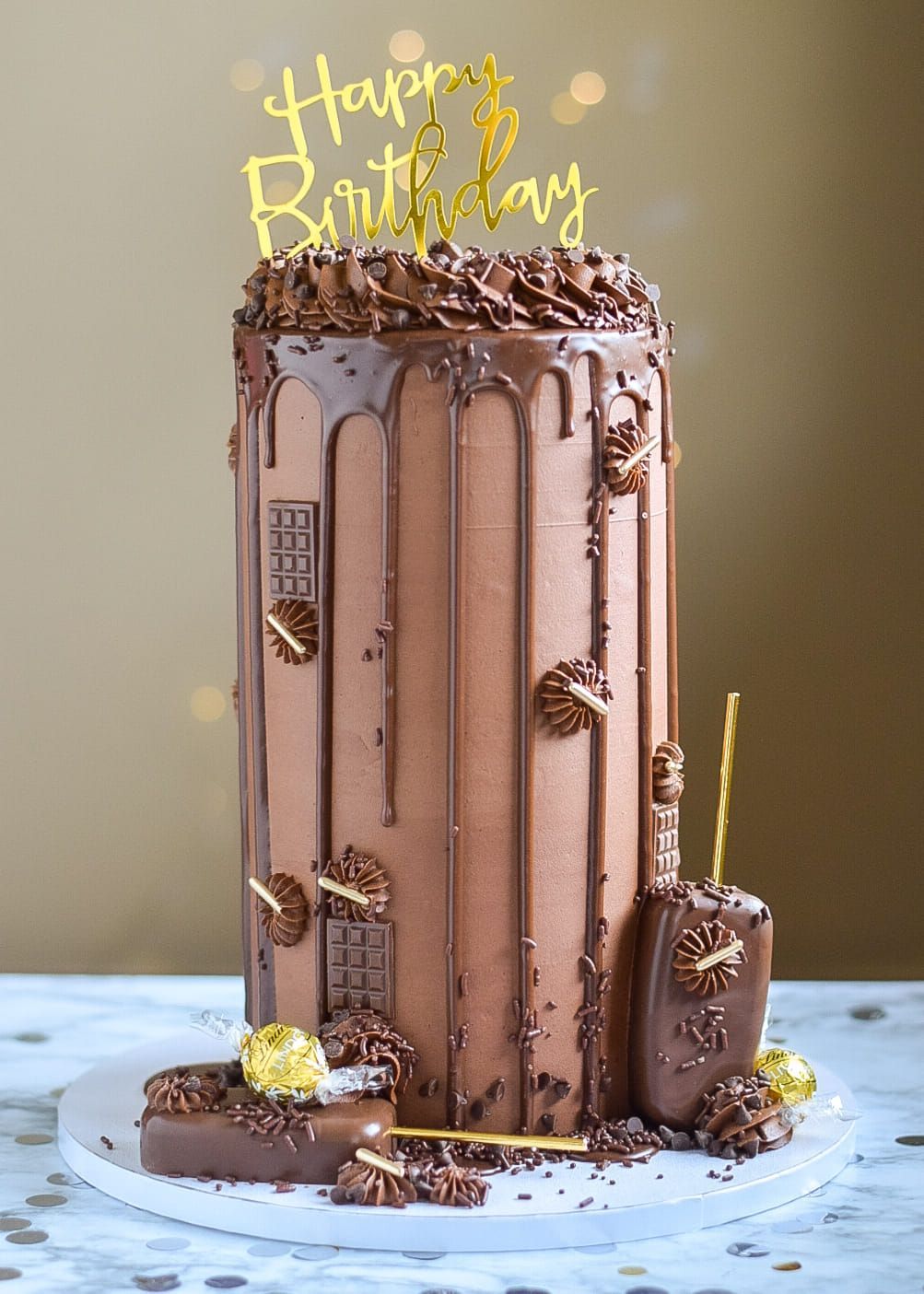 A chocolate birthday cake with a happy birthday topper is sitting on a table.