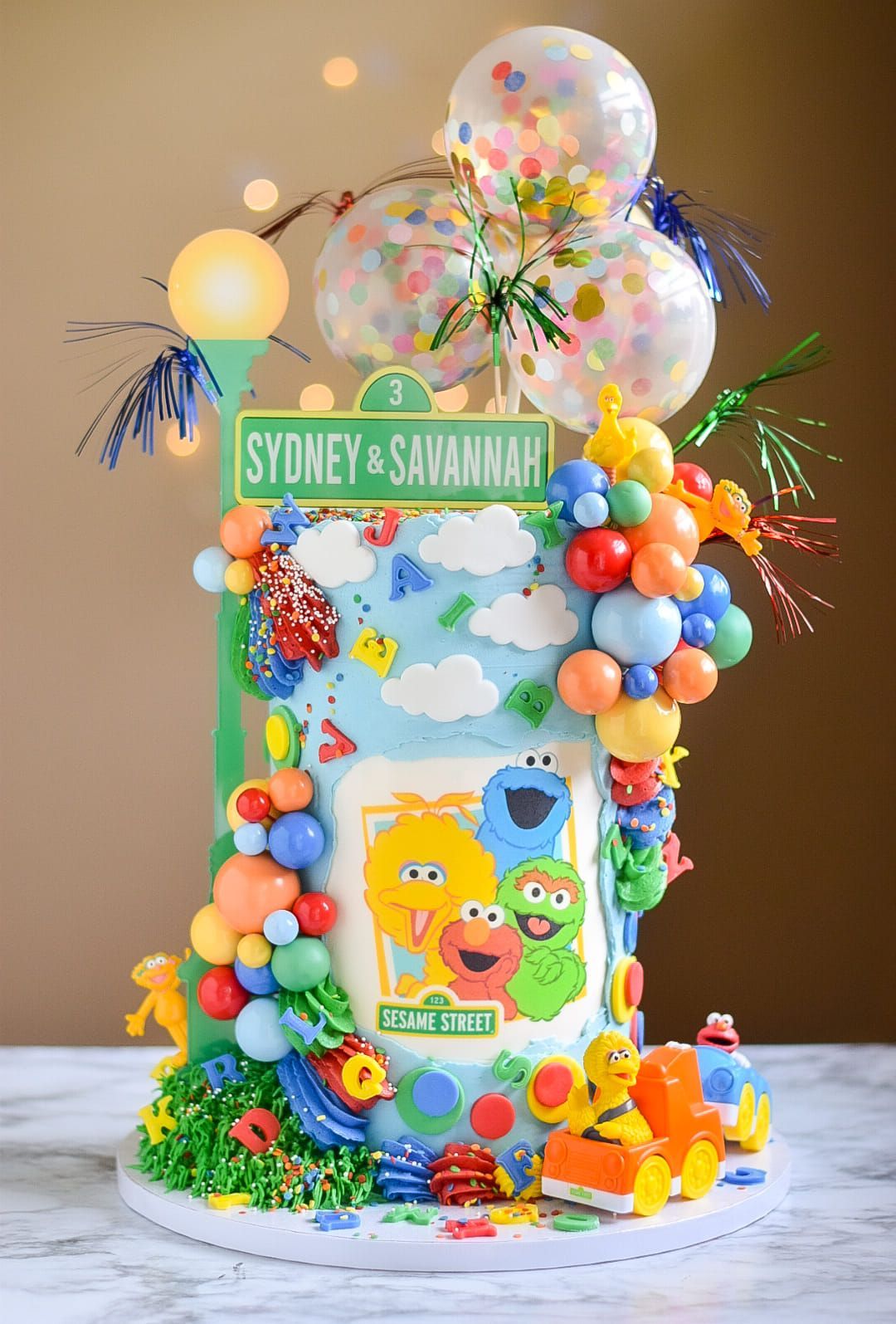 A cake decorated with sesame street characters and balloons on a table.