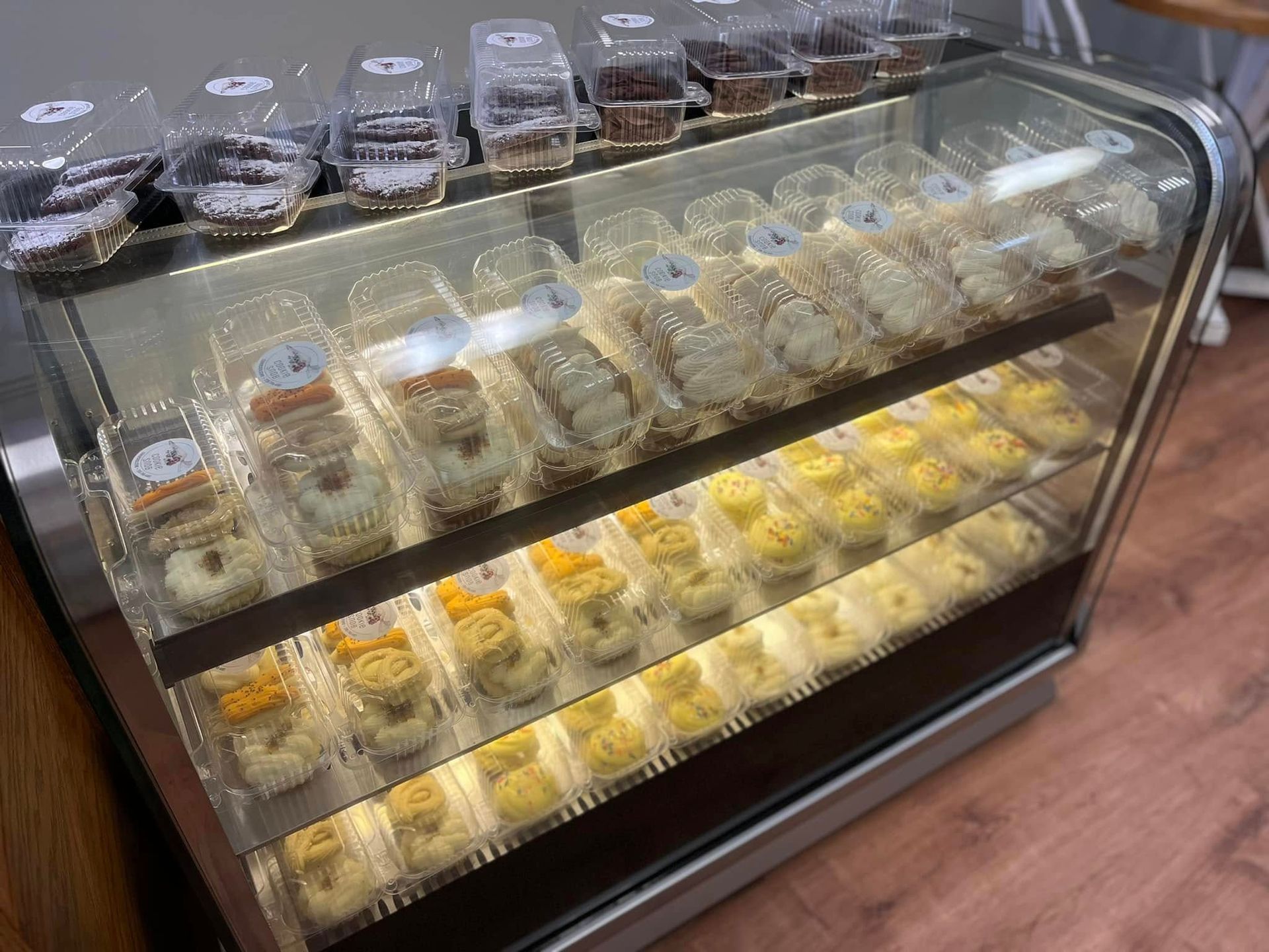 A display case filled with cupcakes and donuts in plastic containers.