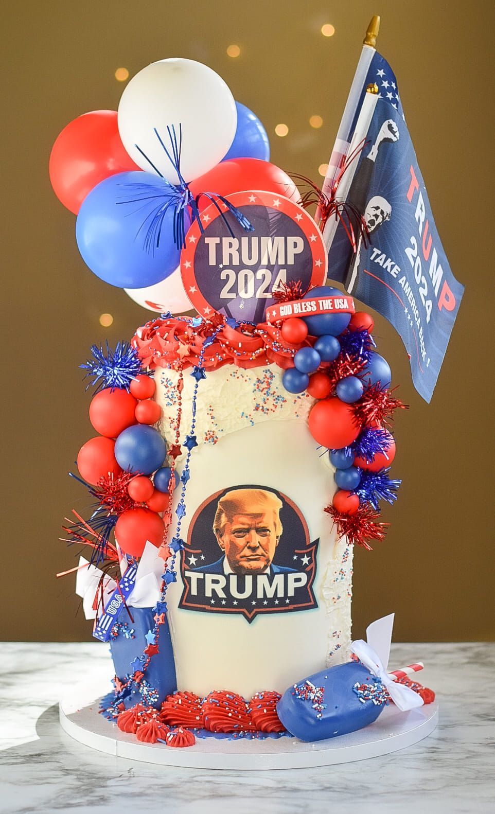 A white cake decorated with red and blue Trump 2024 items