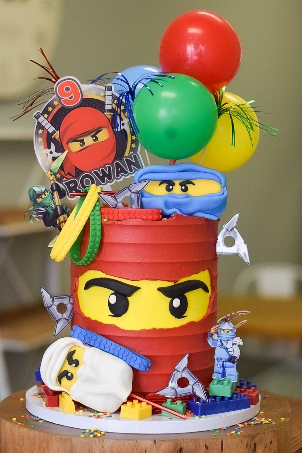 A lego ninjago birthday cake with balloons on top of it.