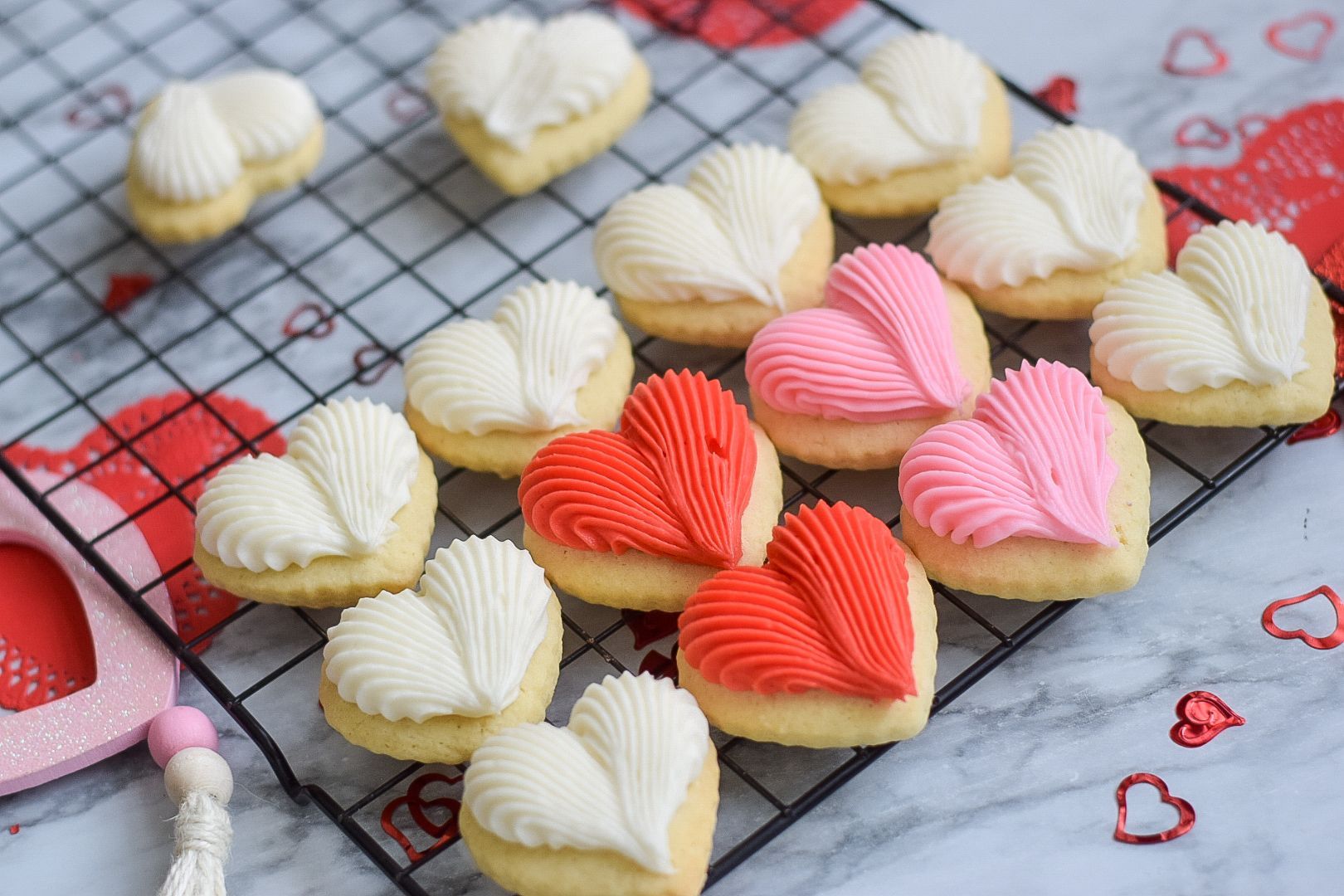 Christmas cookies with green, white, and red frosting and sprinkles on a cooling rack.
