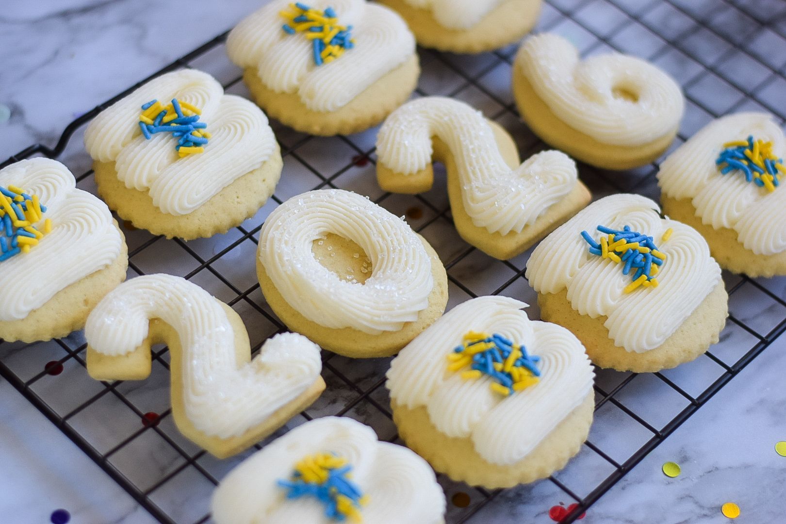 Green cookies with white frosting and gold sprinkles in a box.