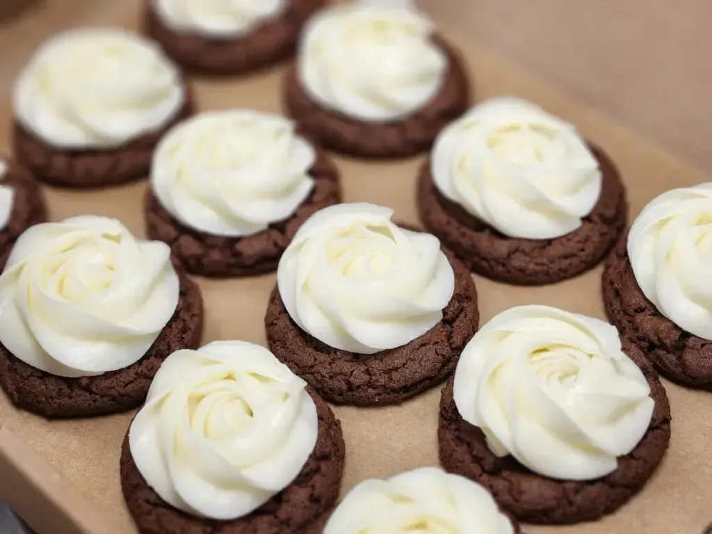 A bunch of chocolate cookies with white frosting on top
