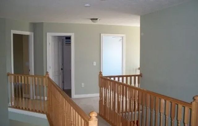 Interior hallway with wooden railings, beige walls, and open doorways
