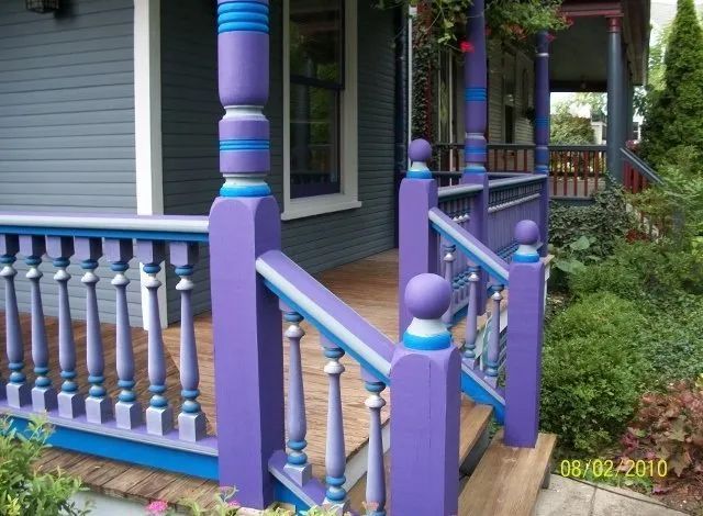 Purple and blue front porch railing with turned balusters and steps beside a house