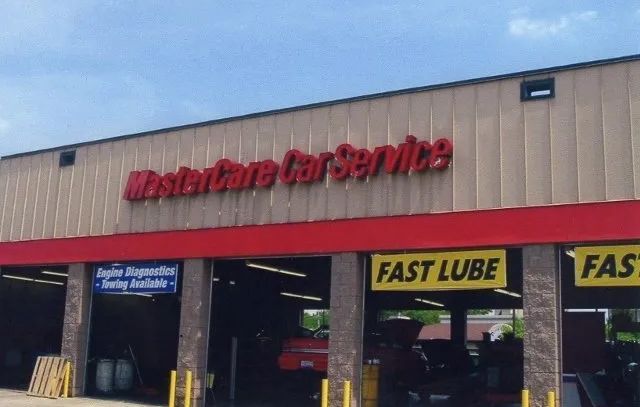 Auto service shop exterior with red signs and a Fast Lube bay under a tan awning