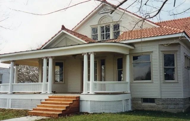Front porch of a beige house with white trim and red roof tiles, viewed from the yard