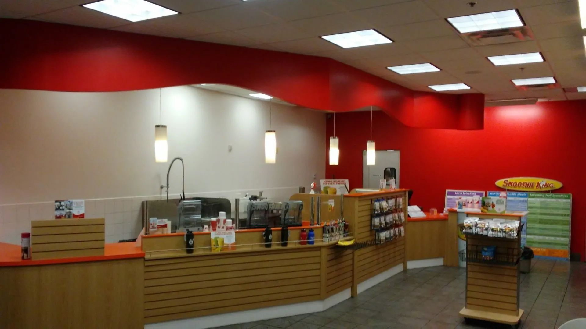 Fast-food restaurant counter area with red walls, menu boards, and seating booths