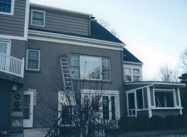 Two-story gray house with white trim and a ladder leaning against an upstairs window