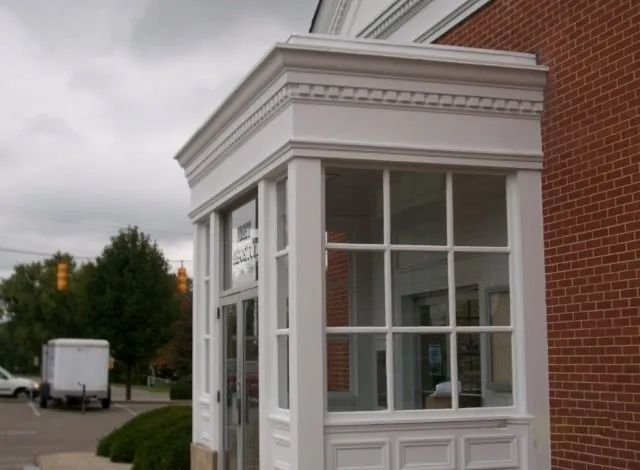 White guard booth with large windows beside a brick building under a cloudy sky