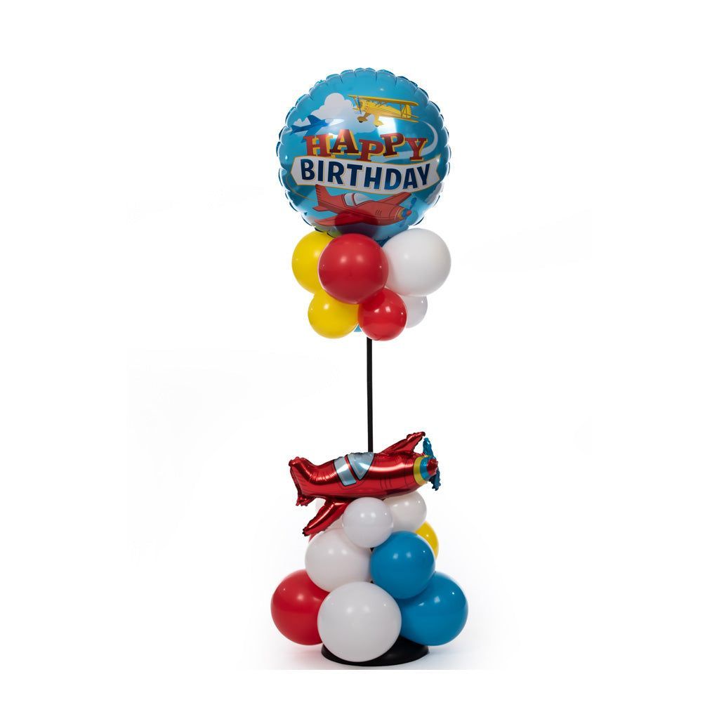 A happy birthday balloon is sitting on top of a stack of balloons.