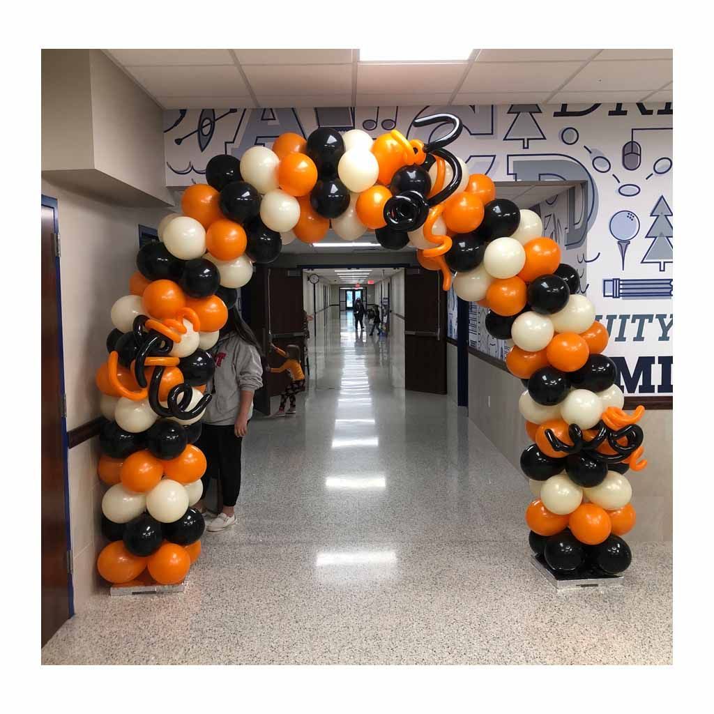 A hallway is decorated with orange and black balloons.