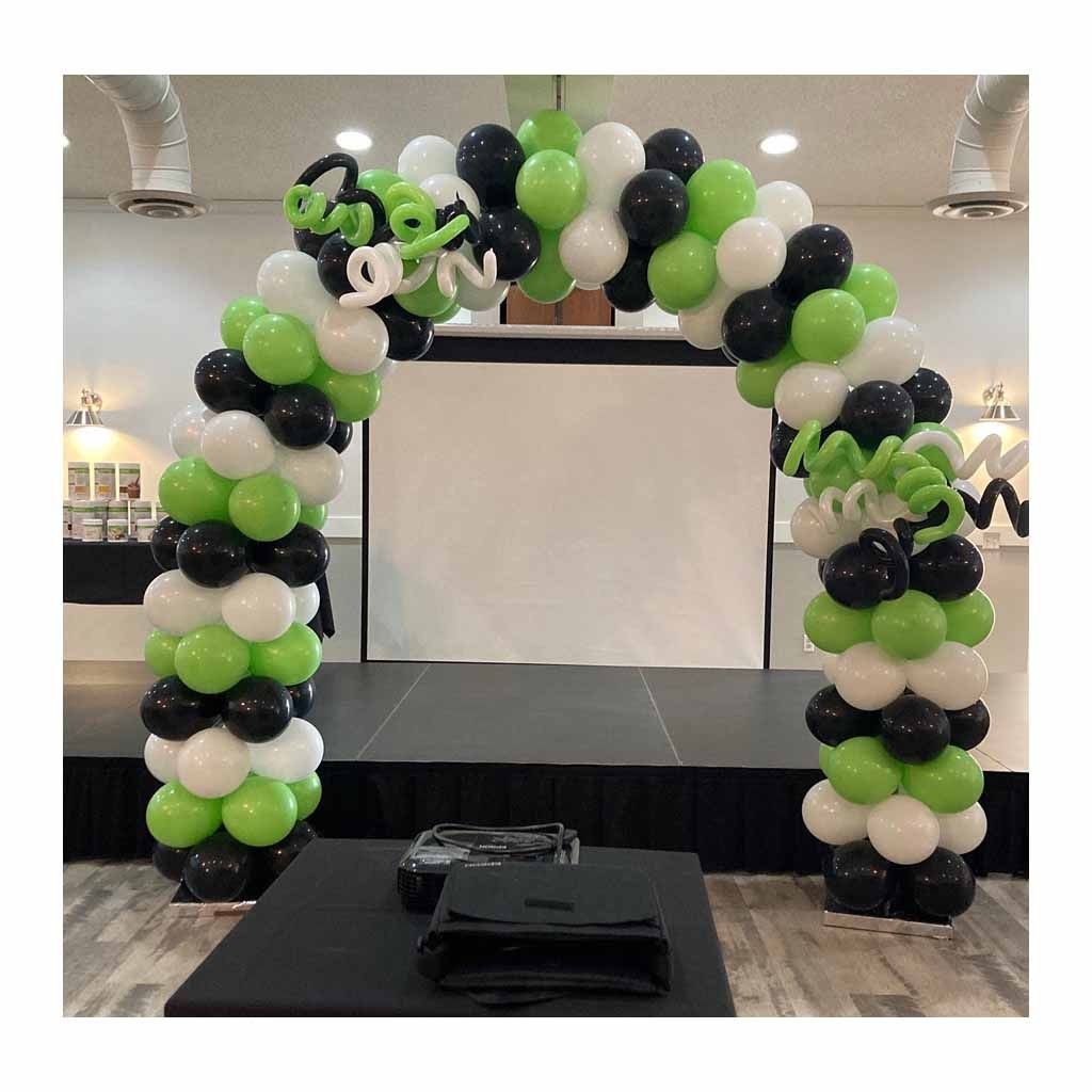 A green , white and black balloon arch is sitting on top of a stage.