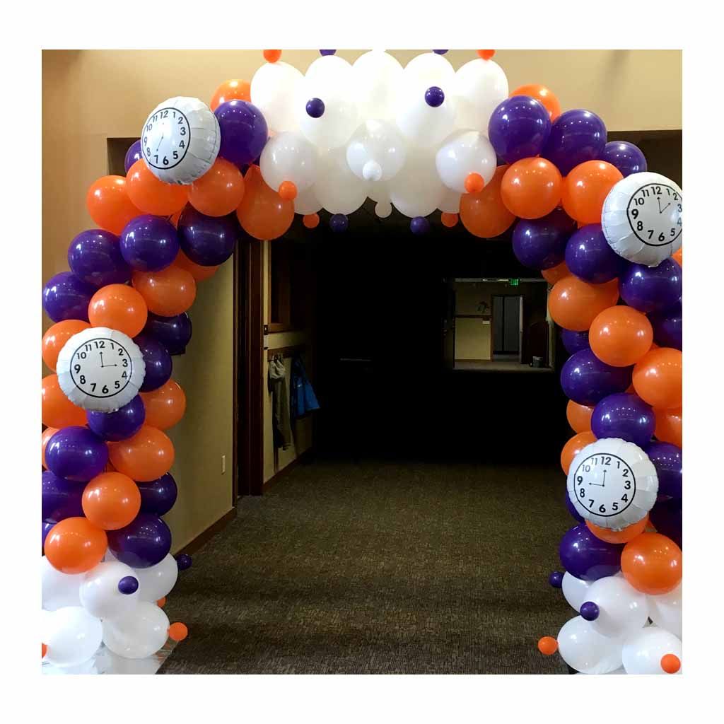 An arch made of orange and purple balloons with clocks on them