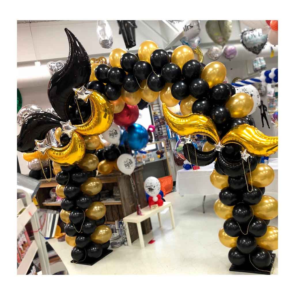 A bunch of black and gold balloons are sitting on top of each other in a room.