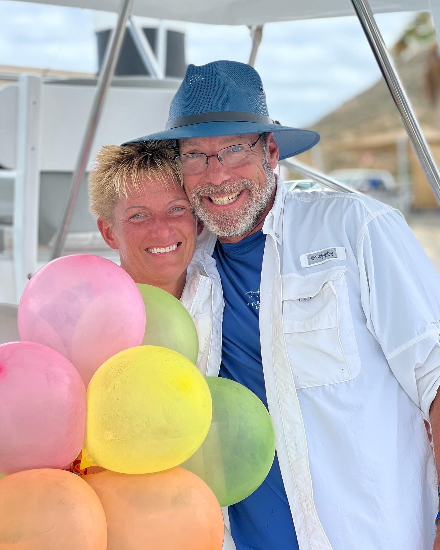 A man and a woman are posing for a picture with balloons.