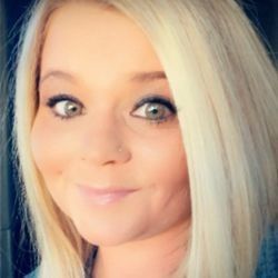 Blonde woman with light eyes and a nose ring smiles directly at the camera.