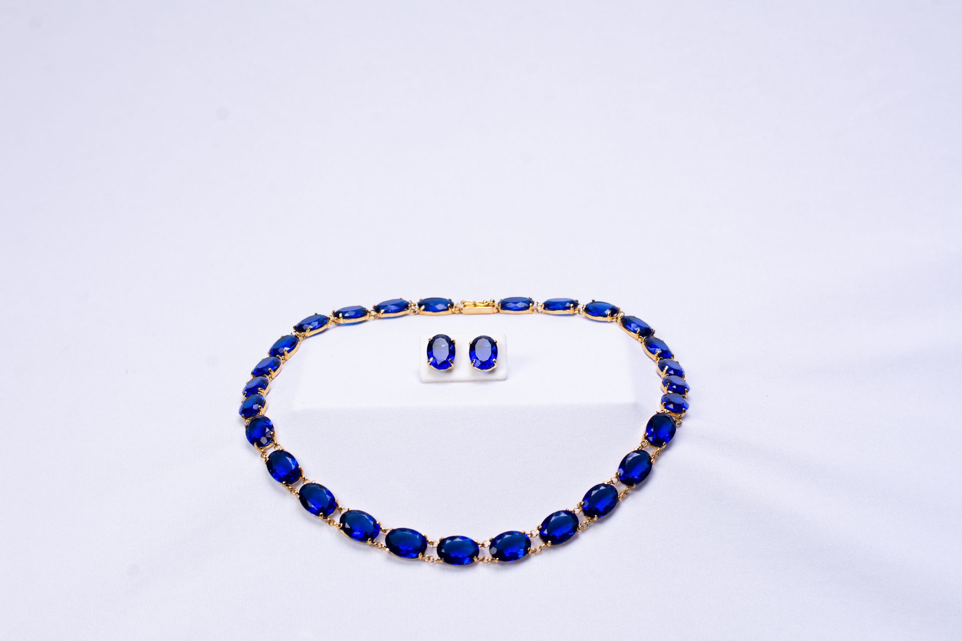 Gold plated statement earrings featuring amethyst (purple gemstones) surrounded by zirconia (clear gemstones), imperial topaz (golden-pink gemstones), tourmaline, blue and yellow topaz (golden gemstones), and garnet (red gemstones)