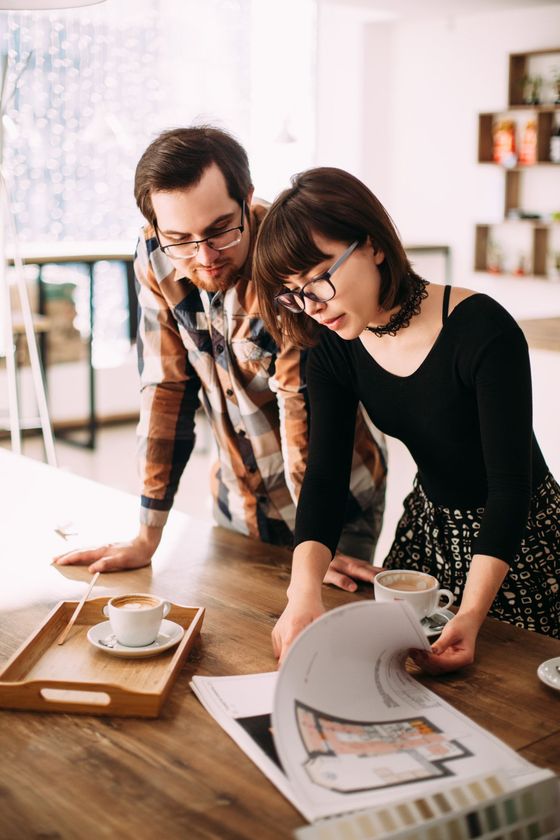 A man and a woman are looking at a drawing on a table.