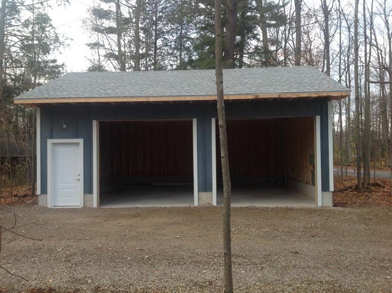 A garage with two doors and a tree in front of it