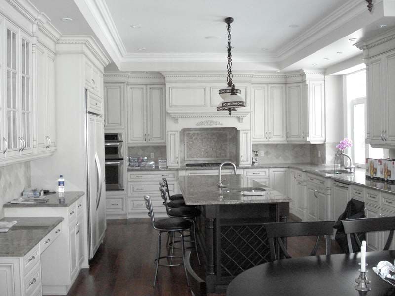 A kitchen with white cabinets and a large island in the middle