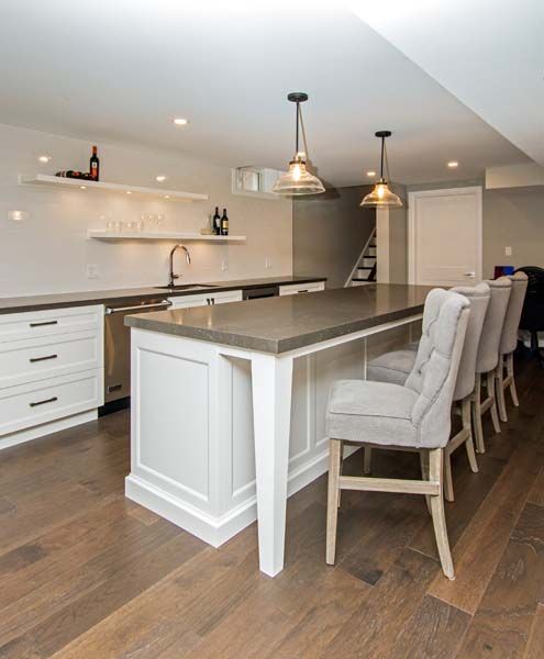 A kitchen with a large island and a row of chairs.
