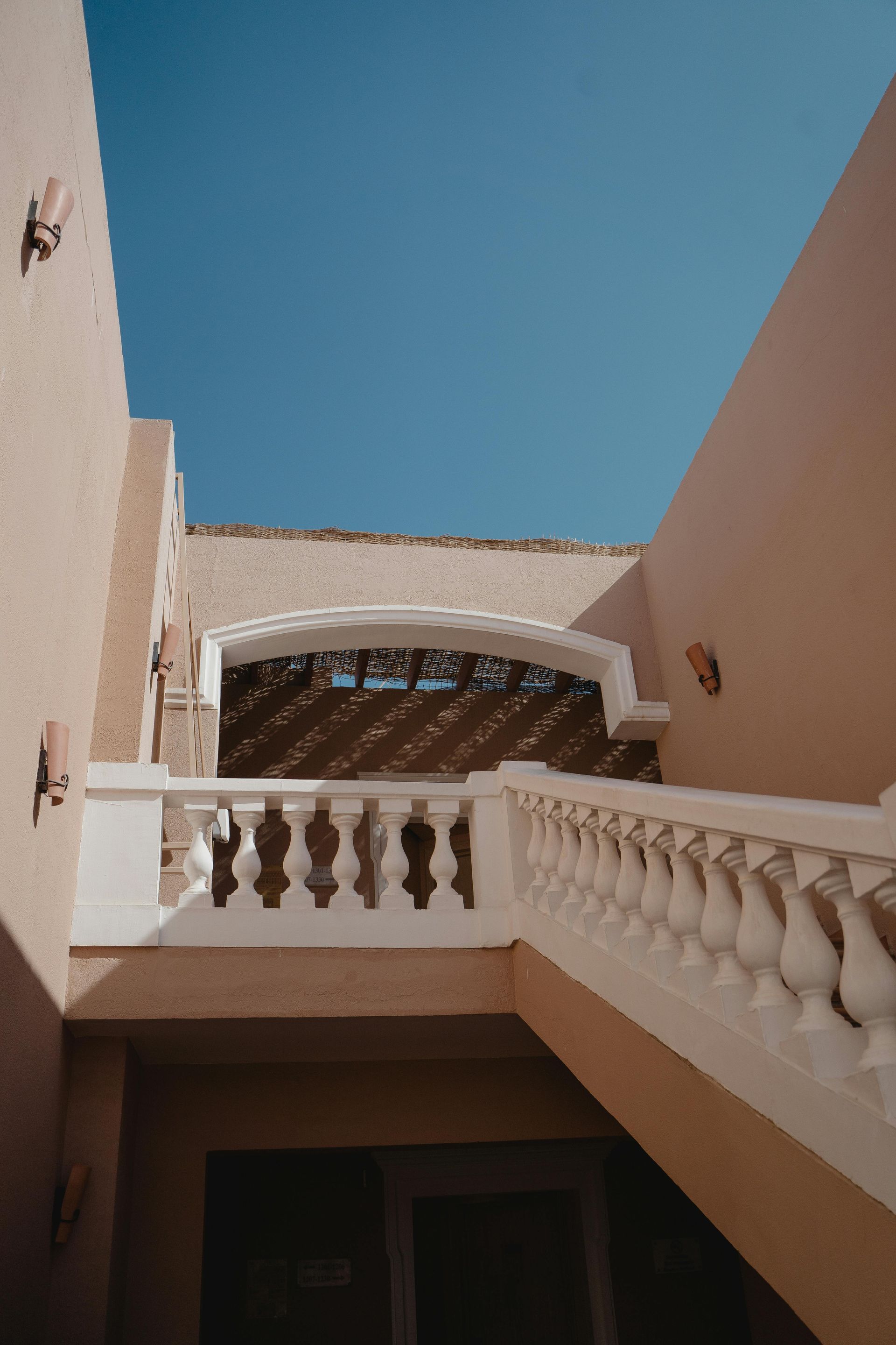 A staircase leading up to a balcony with a blue sky in the background.