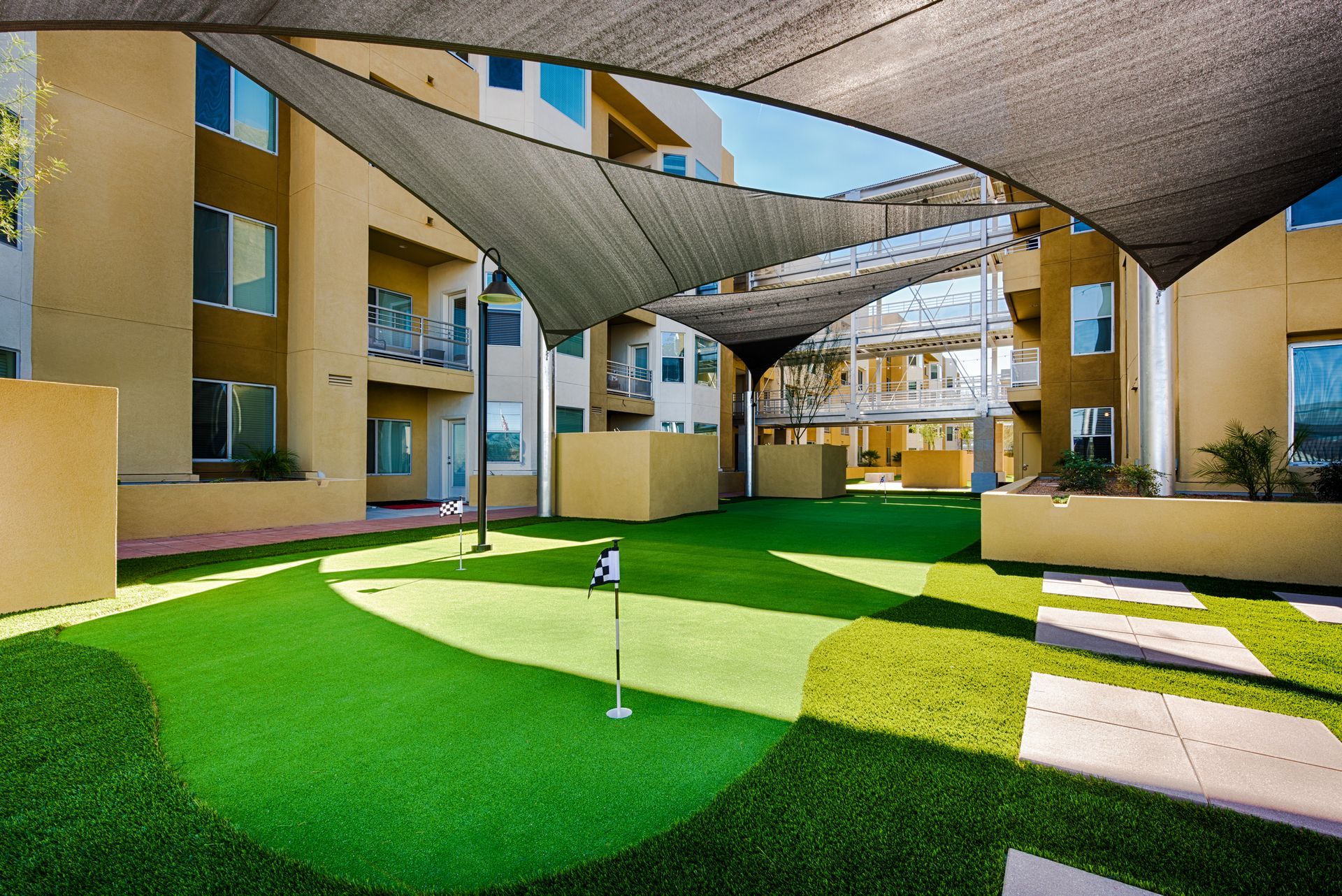A putting green in front of a building under an umbrella.
