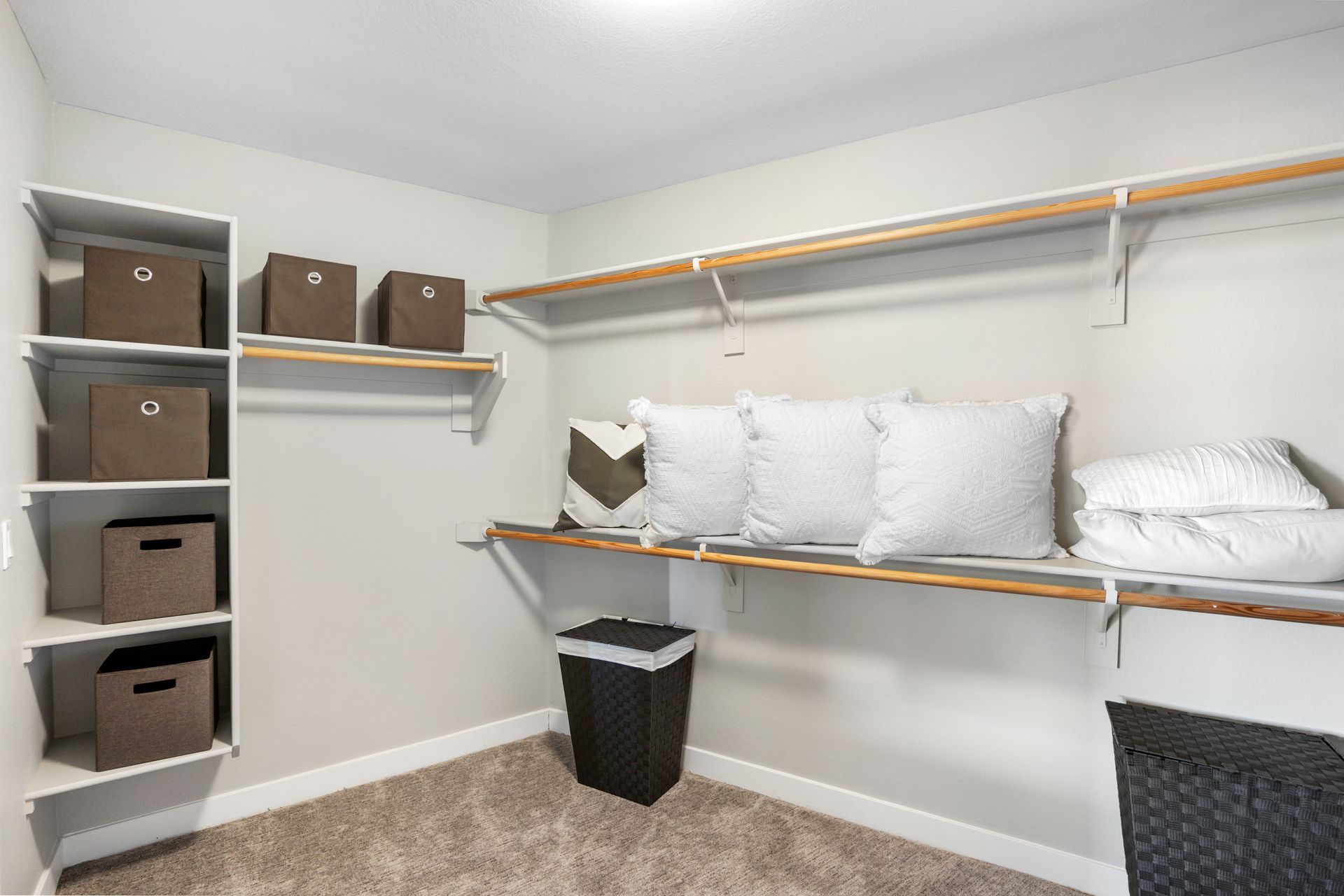 A walk in closet with lots of shelves and pillows.