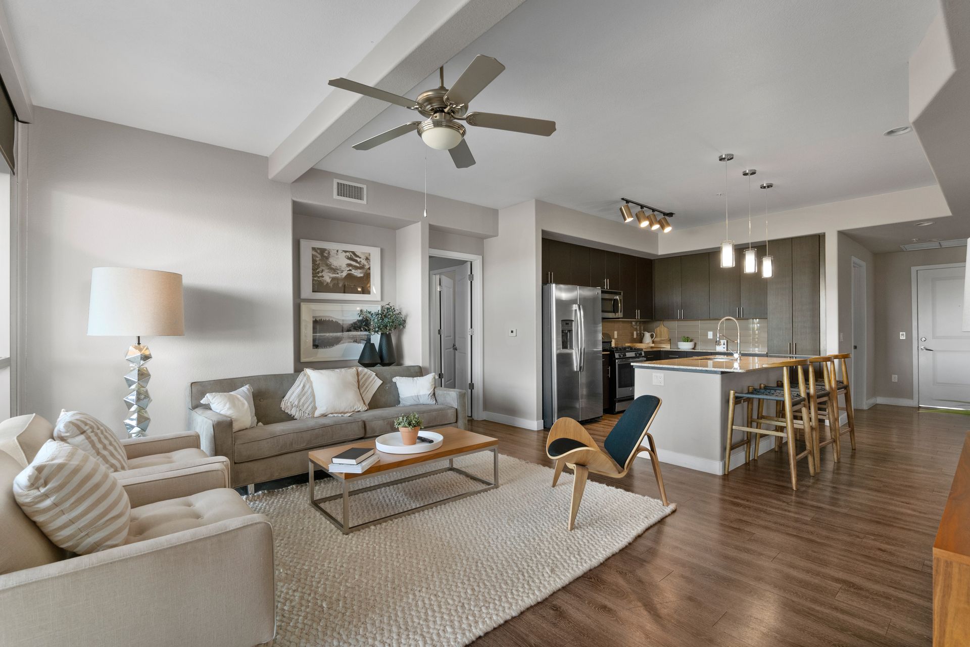 A living room with a couch , chair , coffee table and ceiling fan.