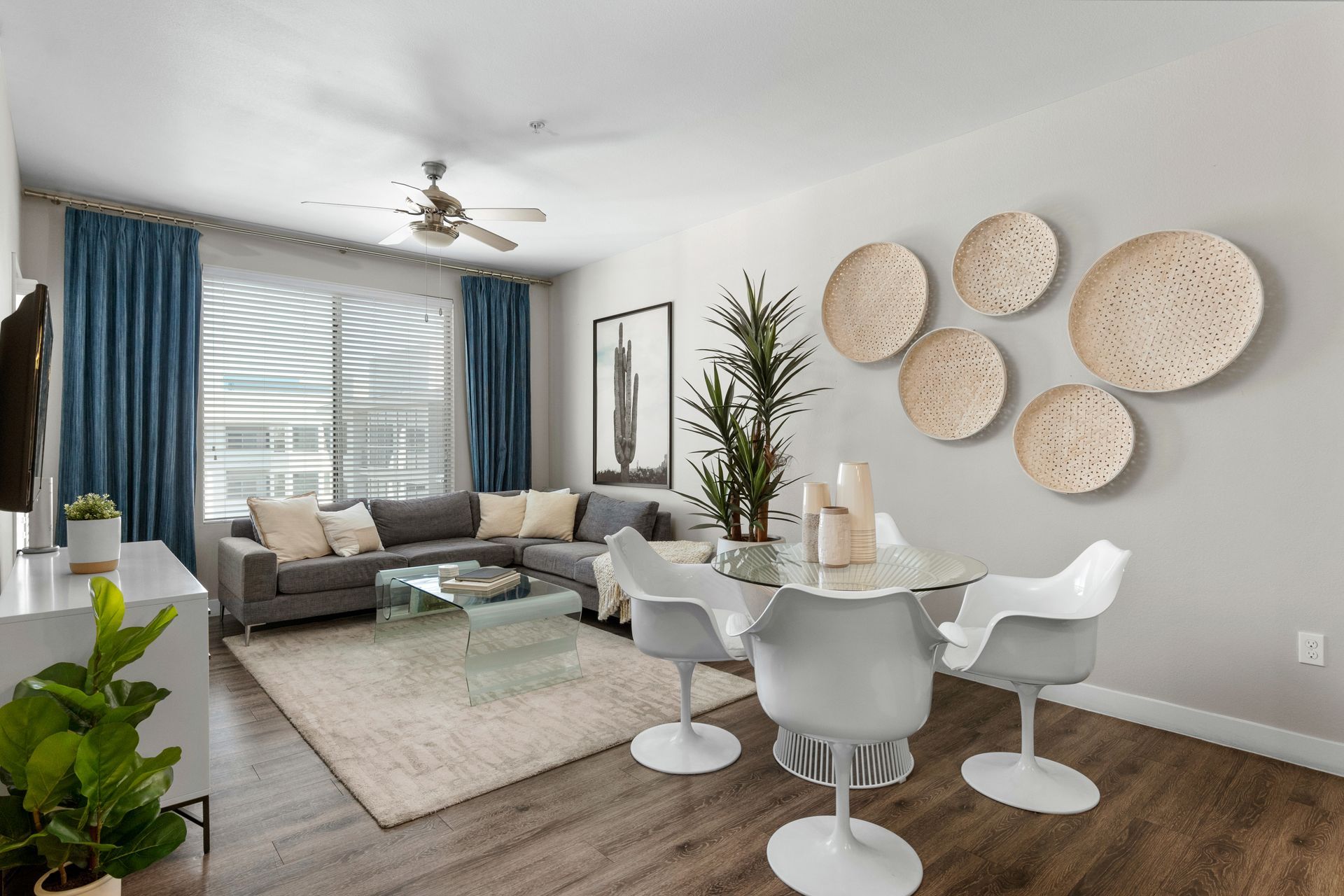 A living room with a couch , table , chairs and a ceiling fan.