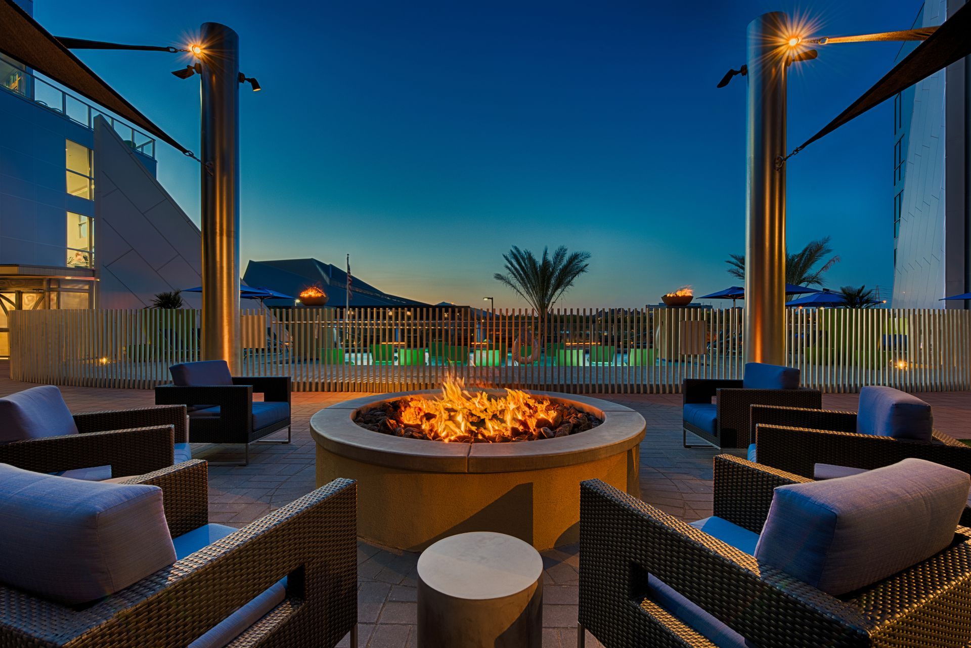A fire pit is surrounded by chairs and a fence.