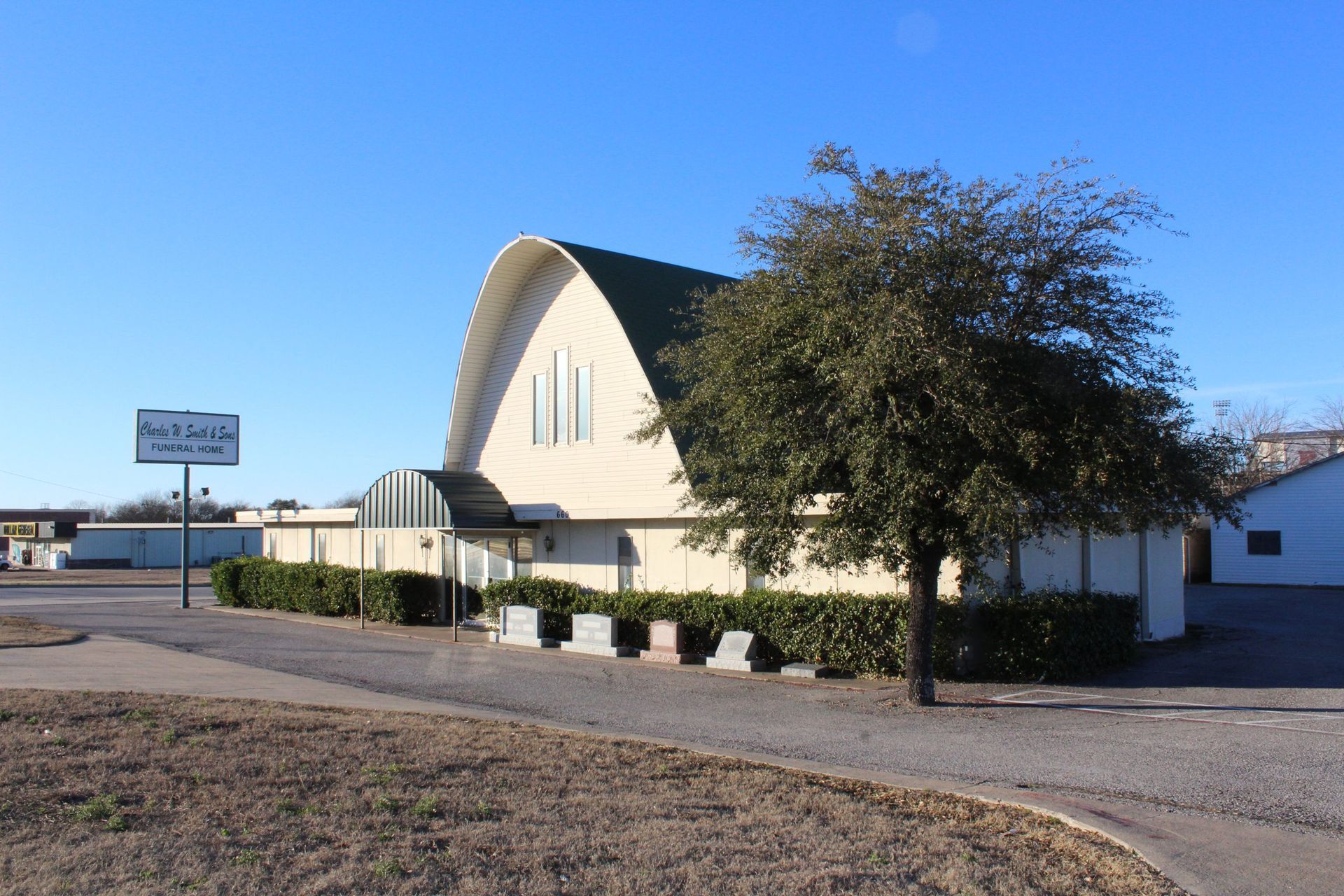 A white building with a green roof and a tree in front of it