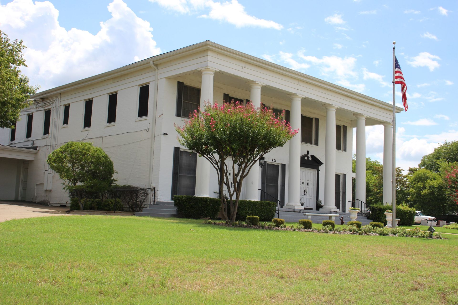 A large white building with columns and a flag in front of it