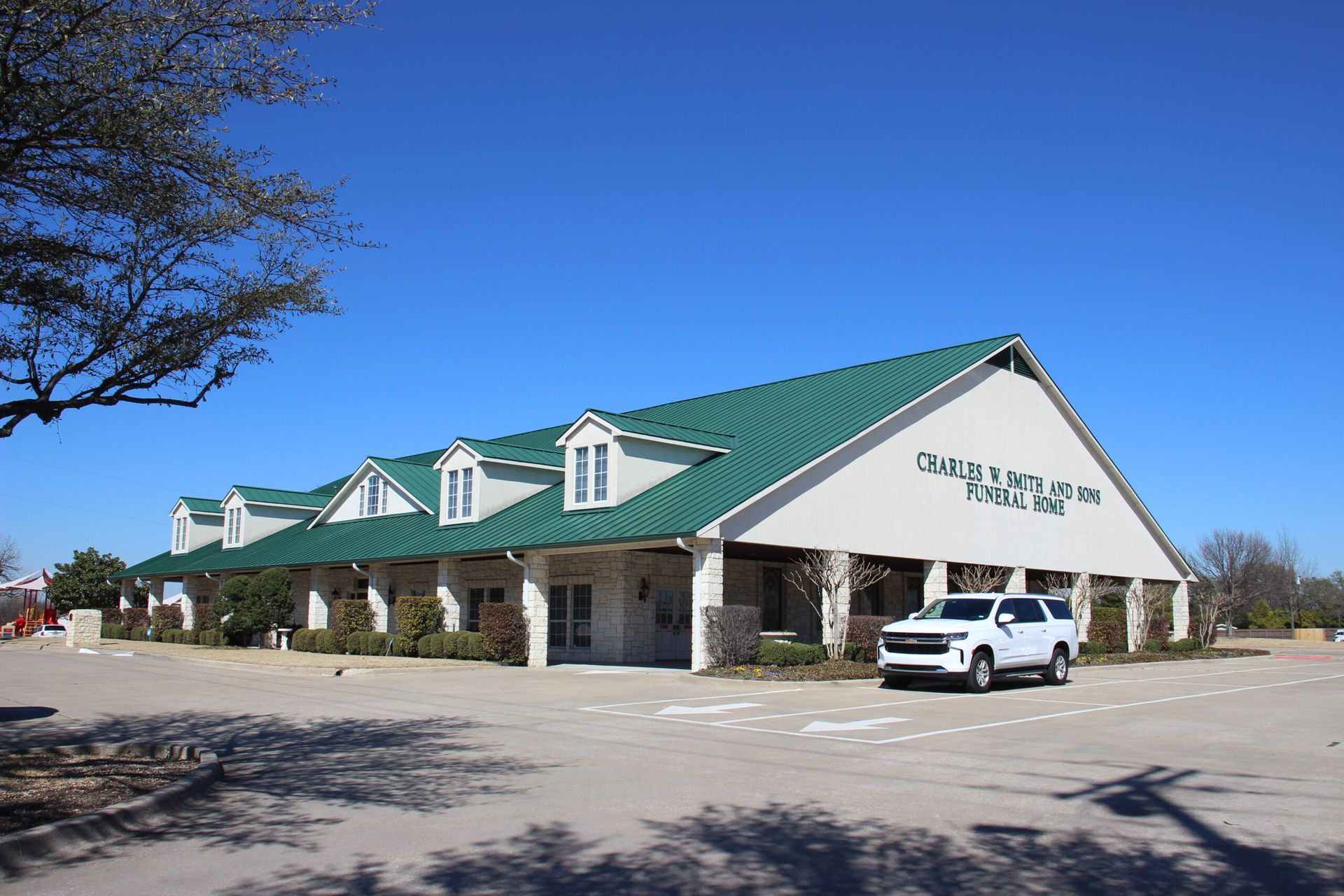 A white suv is parked in front of a building with a green roof.