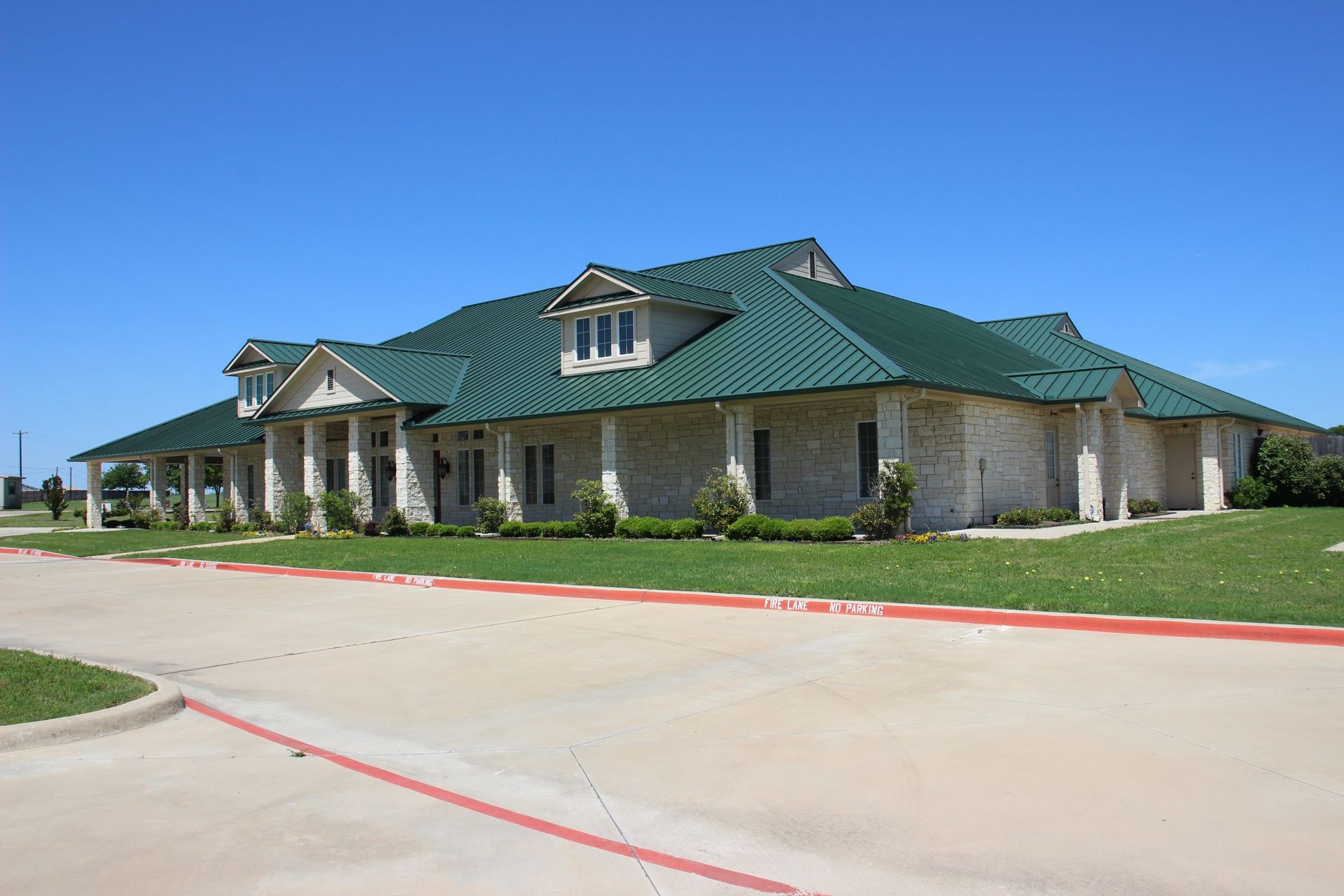A large house with a green roof is sitting on top of a lush green field.