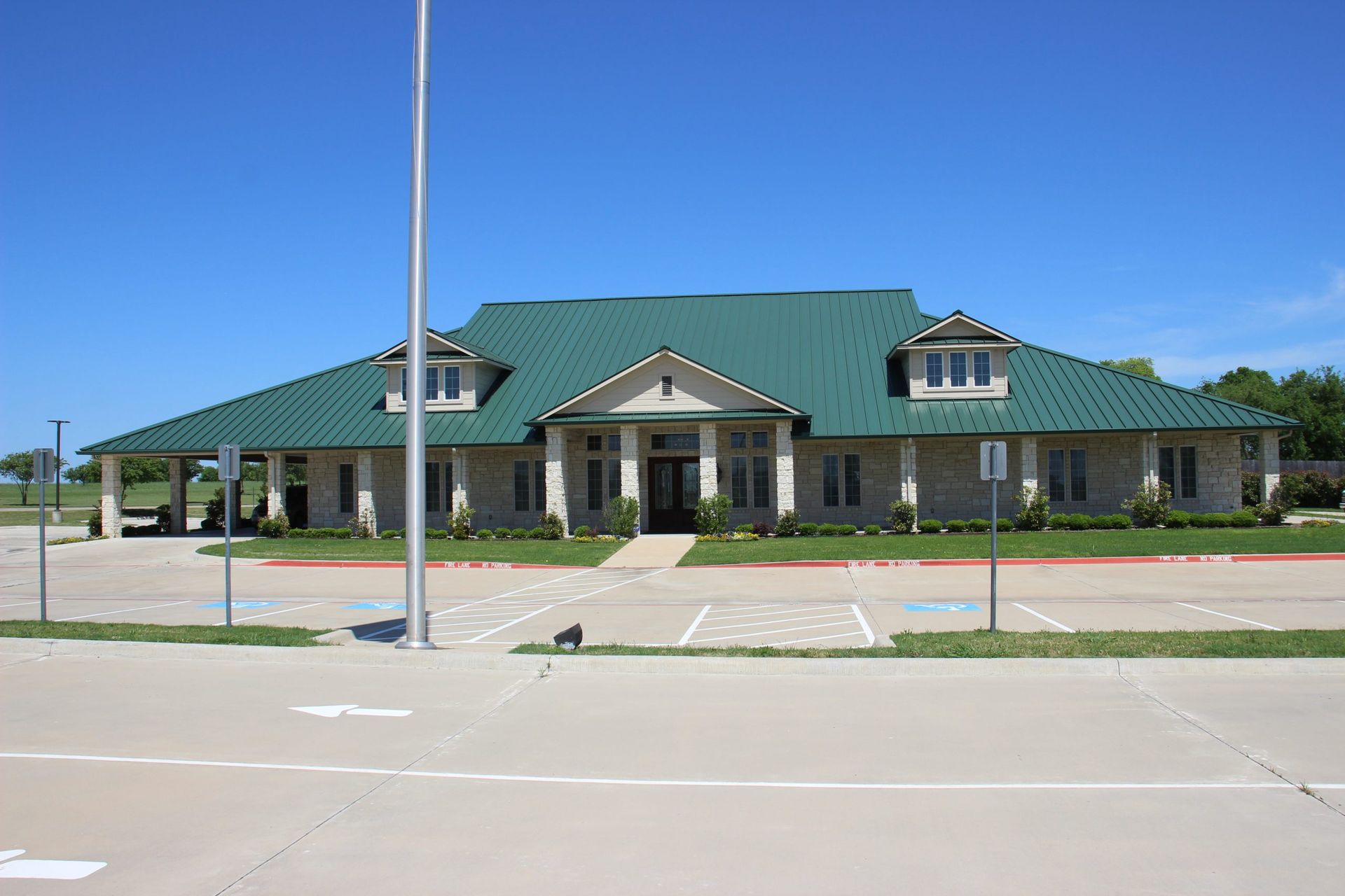 A large house with a green roof and a parking lot in front of it