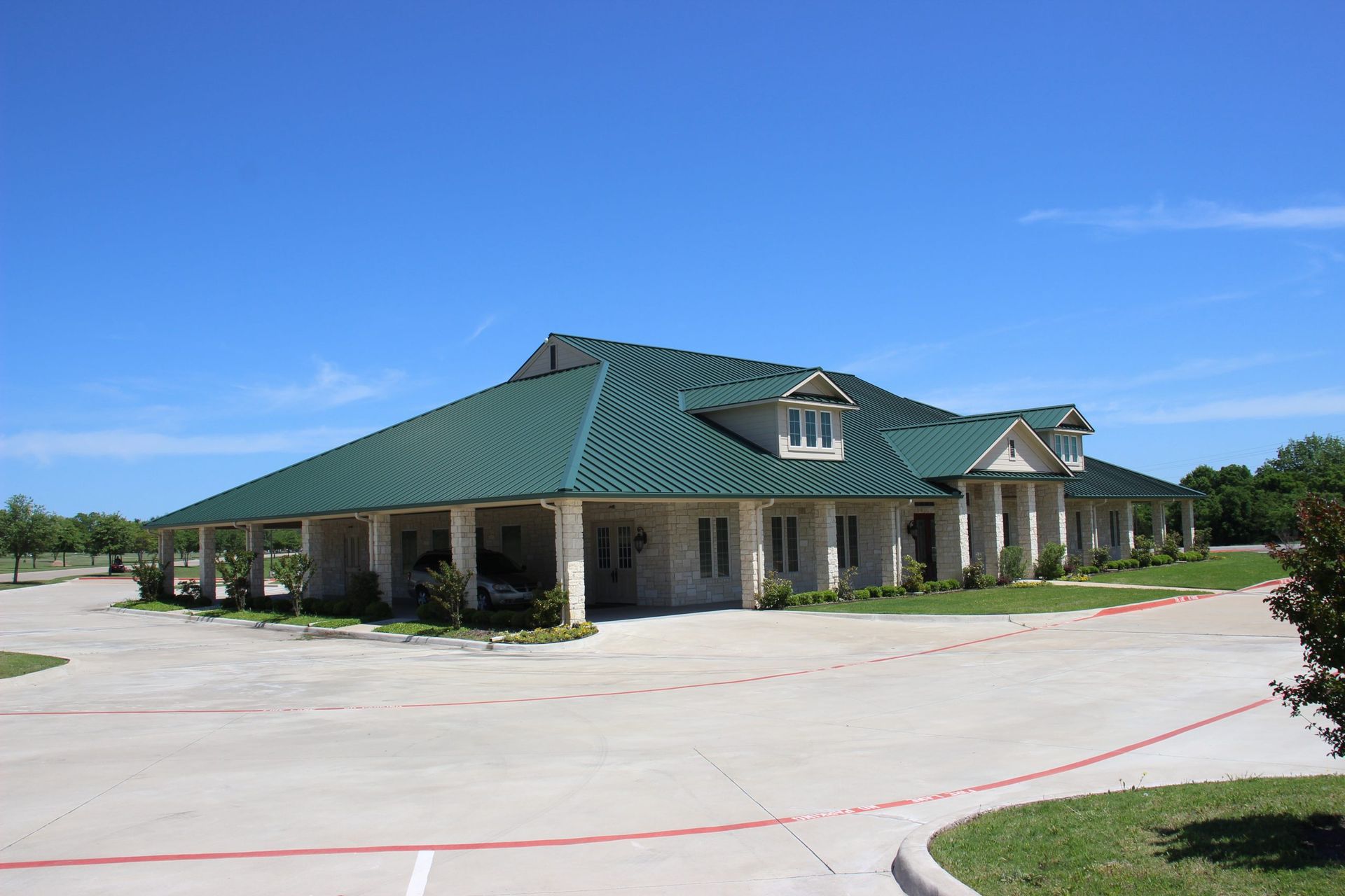 A large white house with a green roof is sitting in a parking lot.