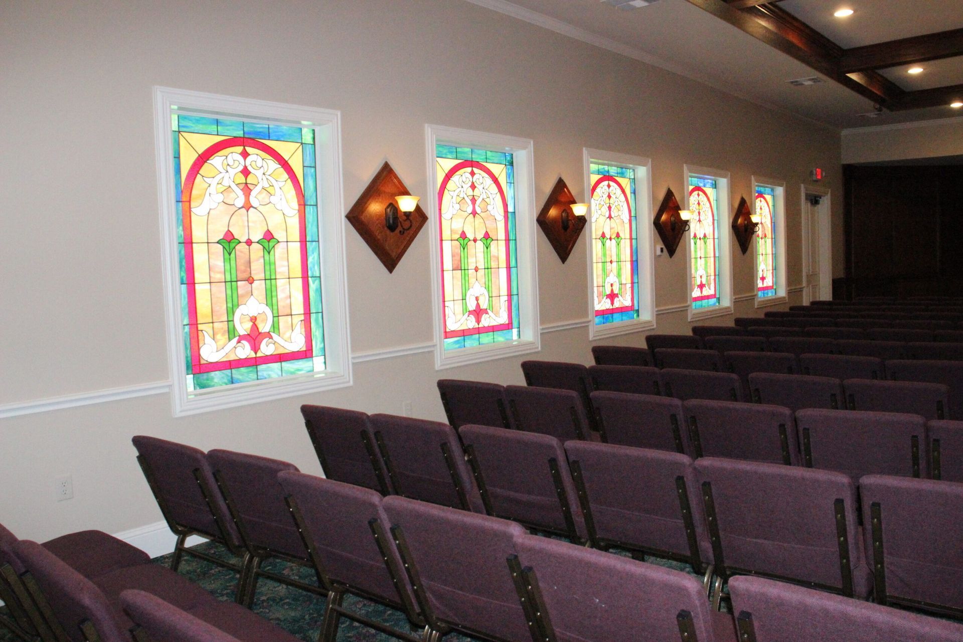 Rows of purple chairs in a church with stained glass windows