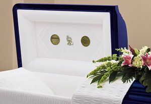 A blue coffin with a white blanket and flowers on it.