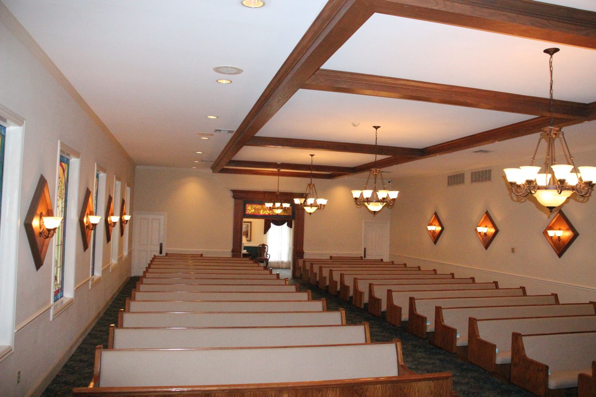 An empty church with rows of benches and a chandelier hanging from the ceiling