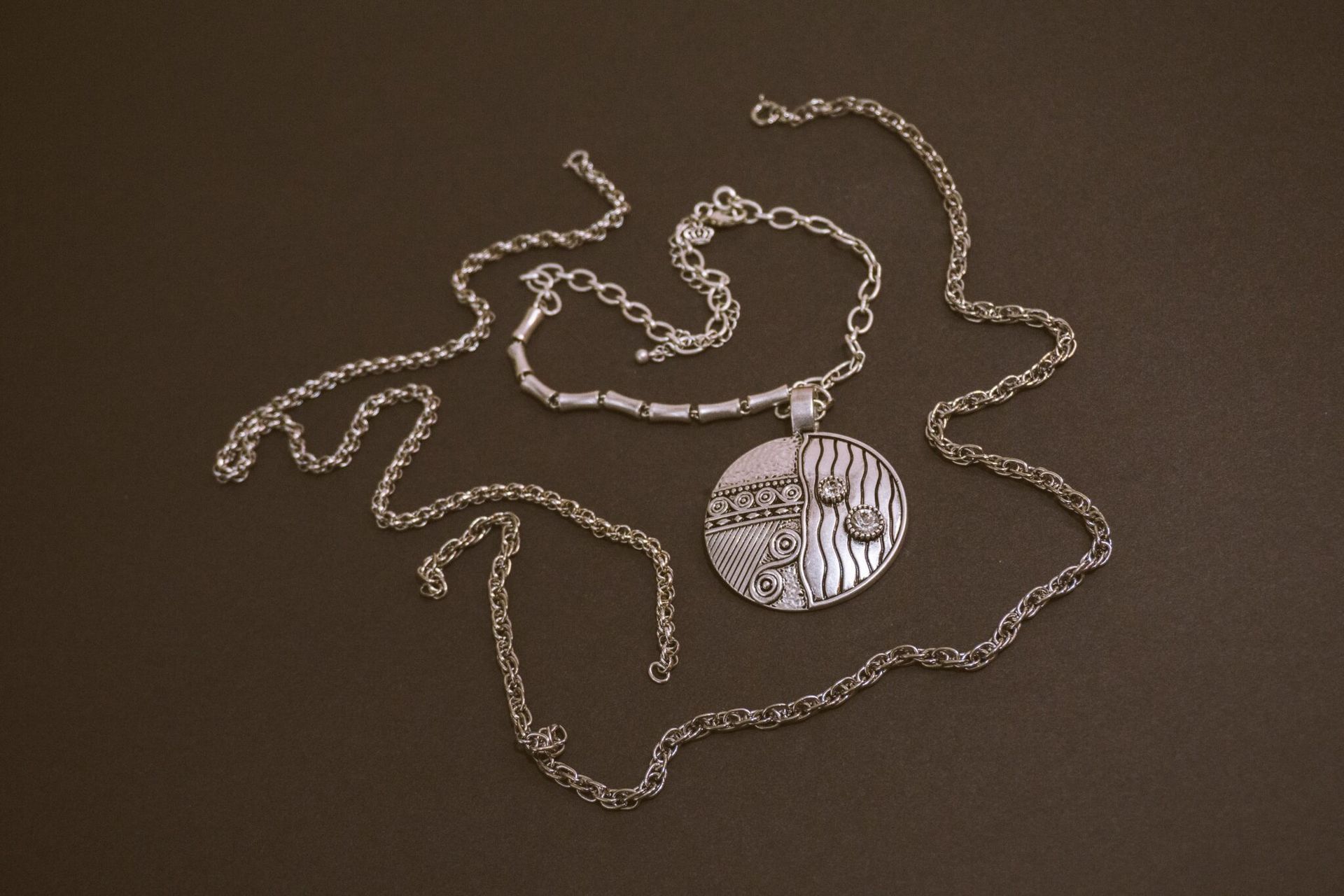 A silver necklace with a round pendant on a chain