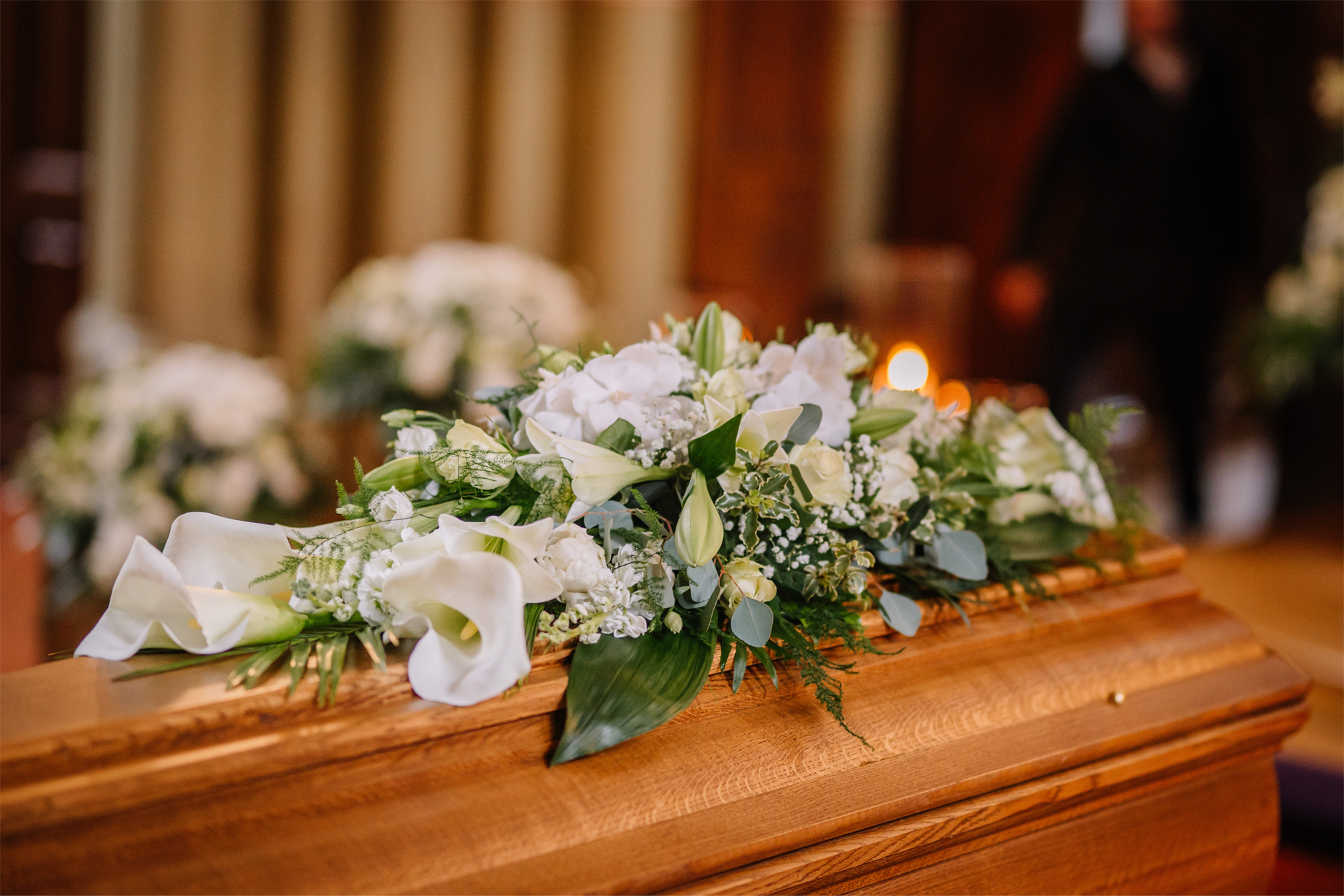 A wooden coffin decorated with white flowers in a funeral home.