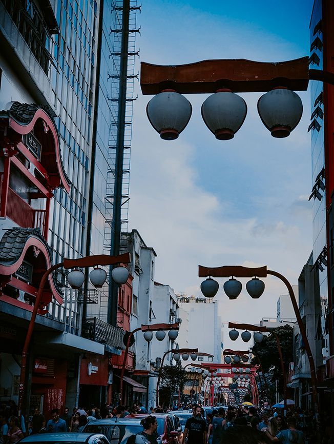 Uma rua movimentada com as típicas lâmpadas de papel japonesas penduradas em postes vermelhos