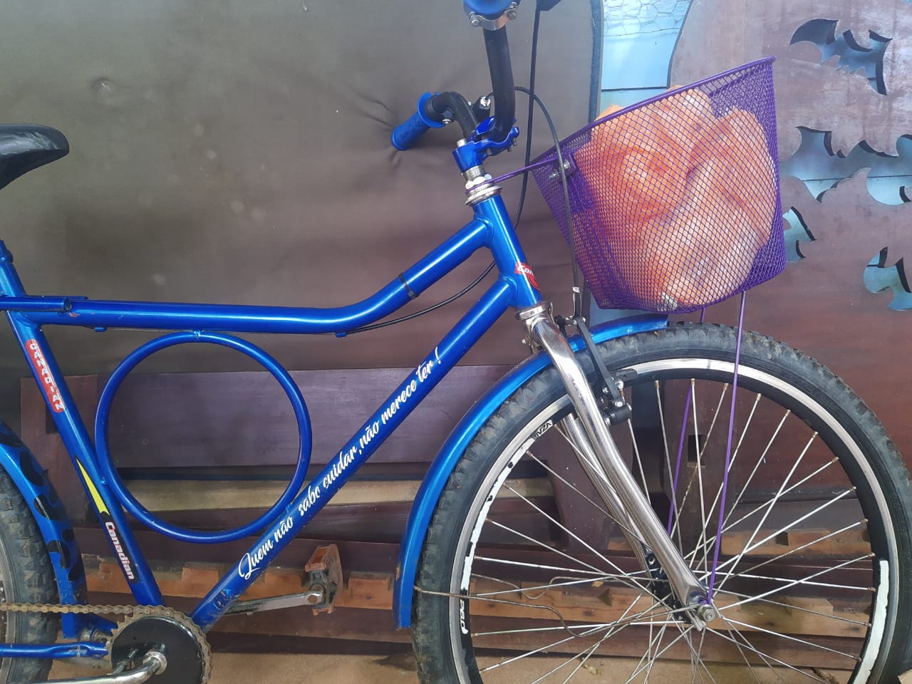 A blue bicycle with a baket that holds a pink plastic bag
