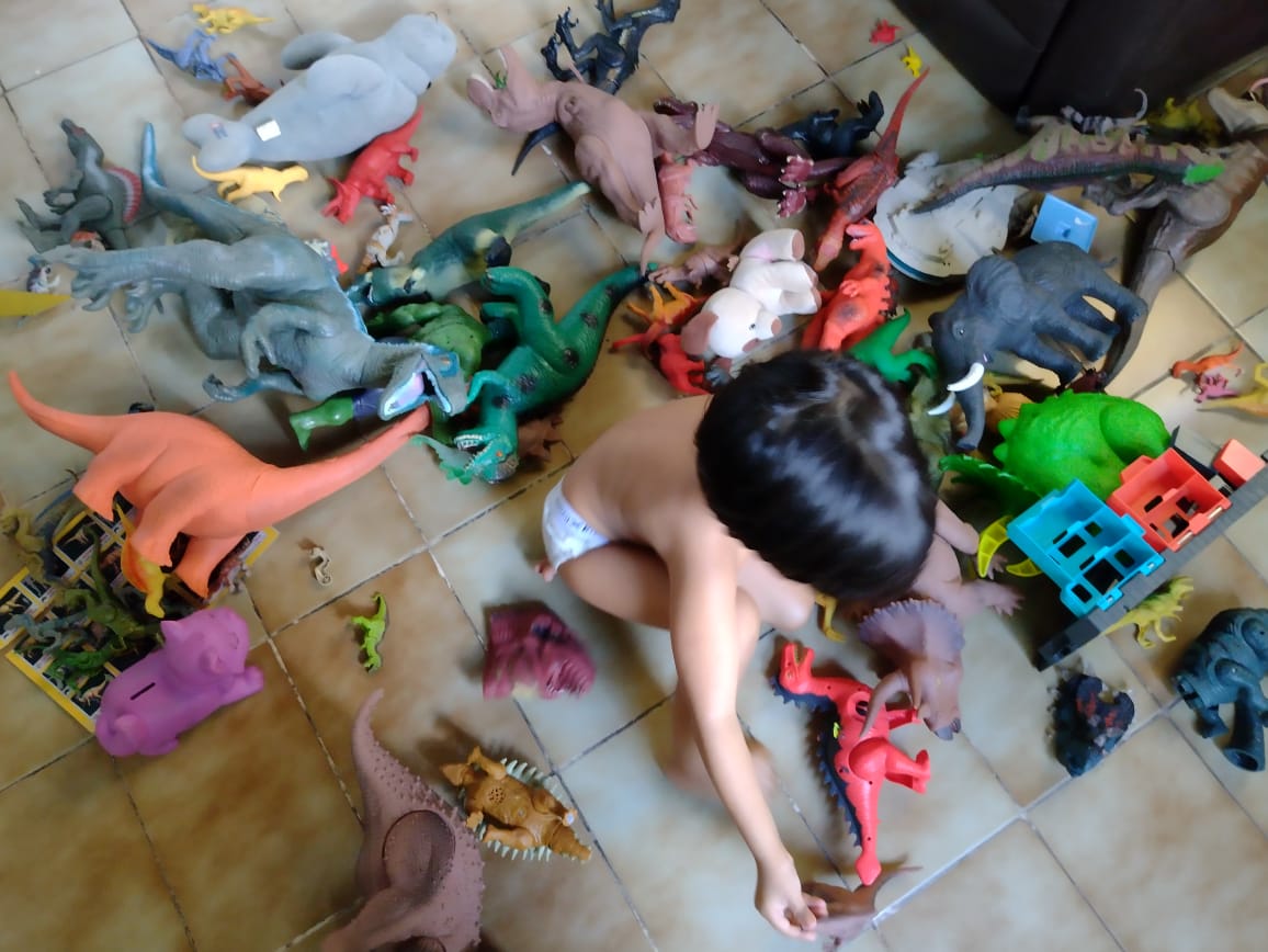 A baby playing on the floor with toys scattered around