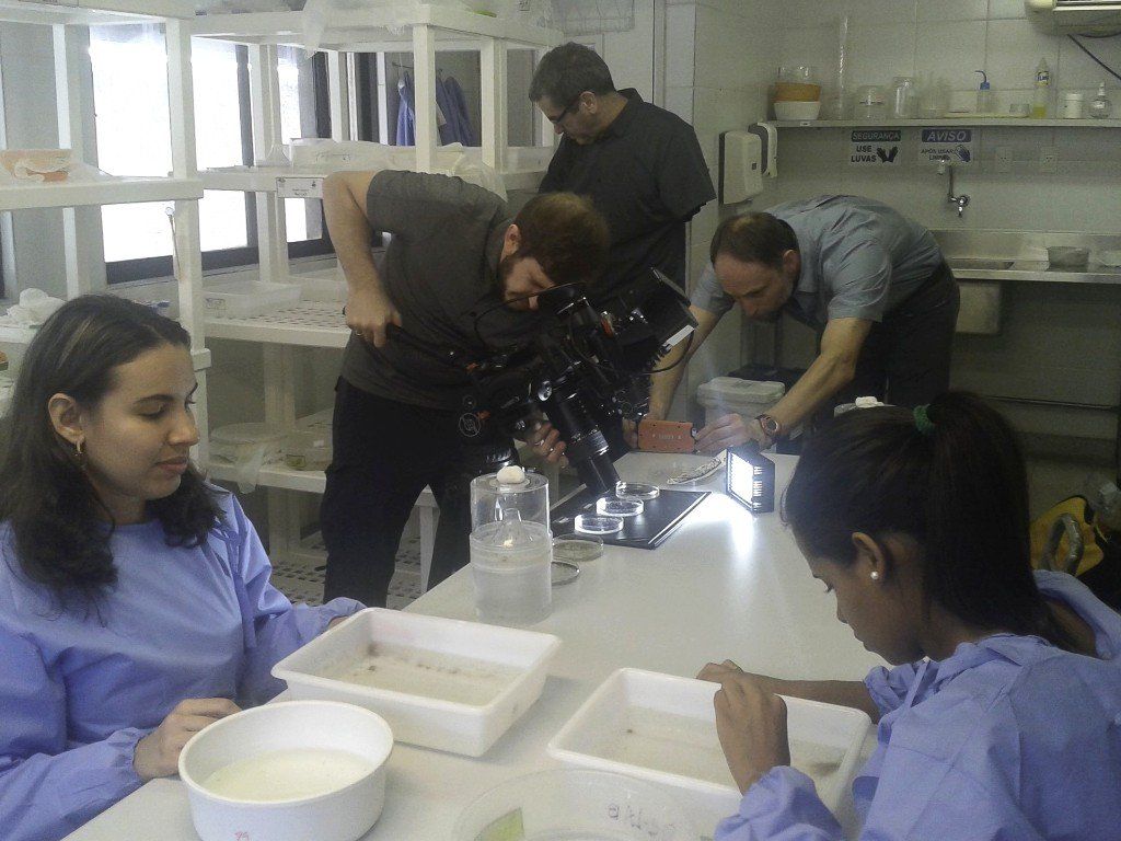 Une équipe filme deux travailleurs de laboratoire assis sur une table