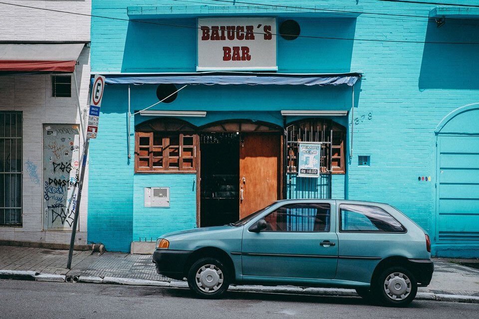 A bar painted blue on the ouside with a blue car parked outside - Photo by Brunno Tazzo