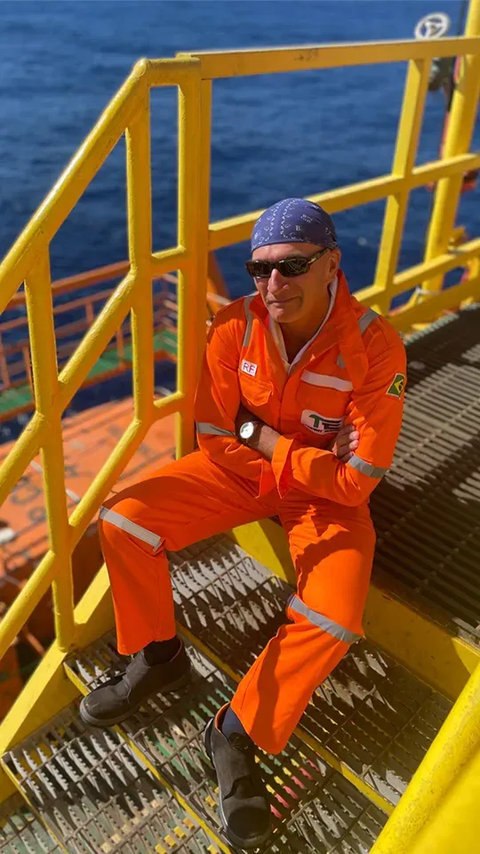 Homem sentado em uma plataforma de petróleo.